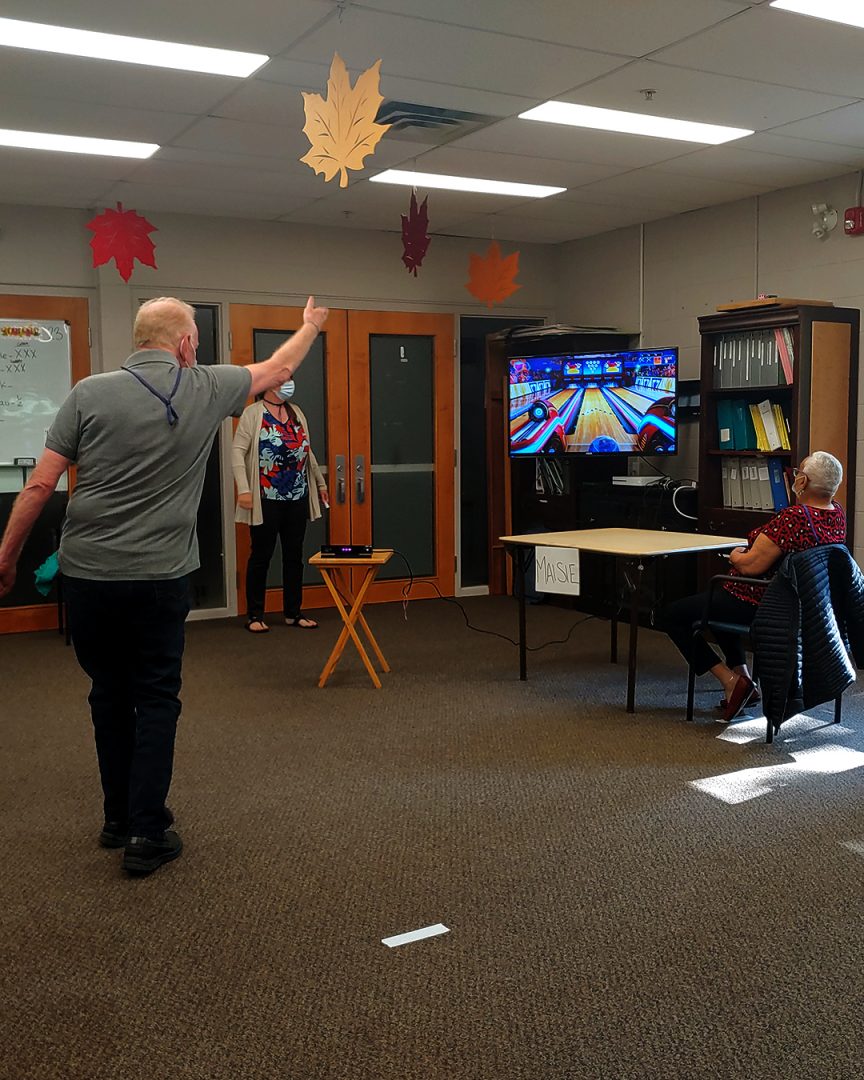 (OSCC55+) Oshawa Senior Community Centres, Northview Branch Adult Day Program members enjoying a game of bowling on an Xbox.