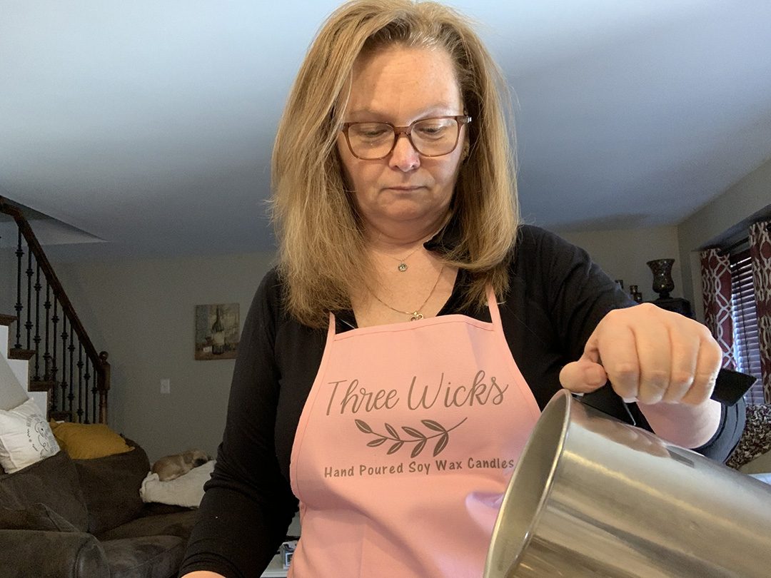 Diane Kennedy, owner of Three Wicks, pours soy wax into candle molds.