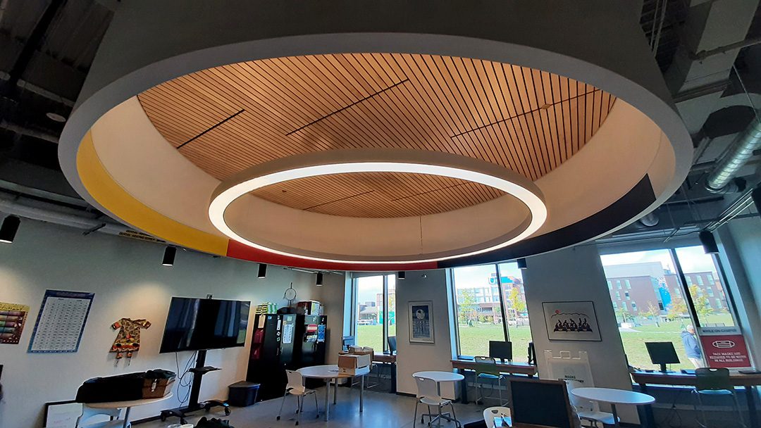 Circular light fixture with Medicine Wheel colours hangs over the First Peoples Indigenous Centre.
