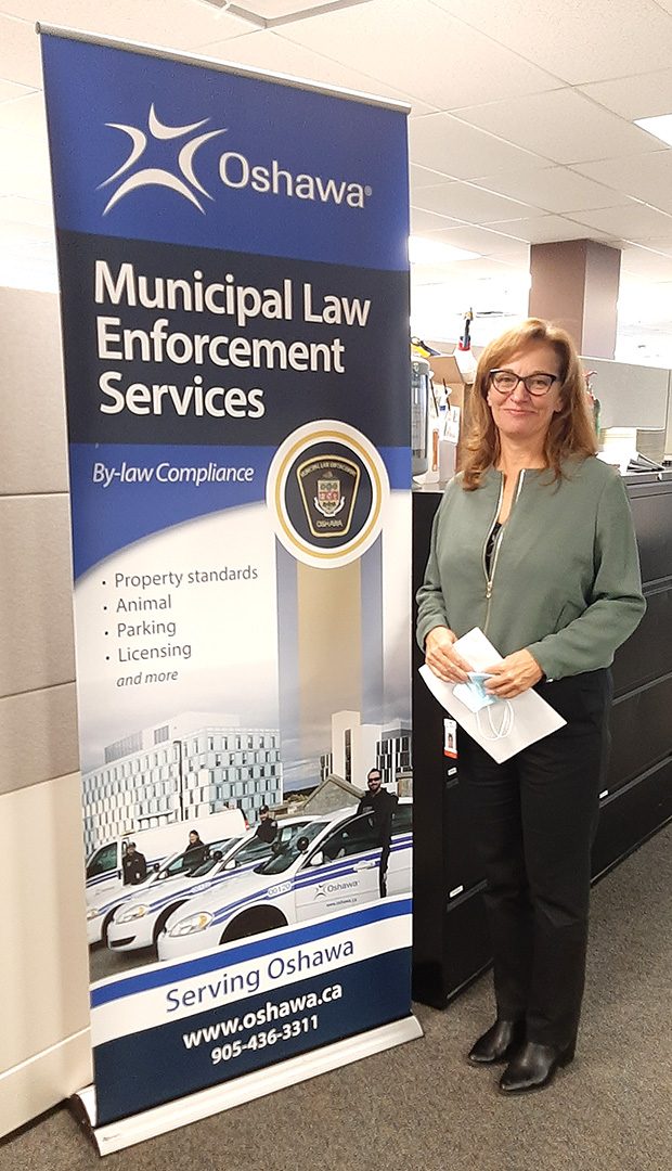 Brenda Jeffs posing next to the 'Municipal Law Enforcement Services' sign.