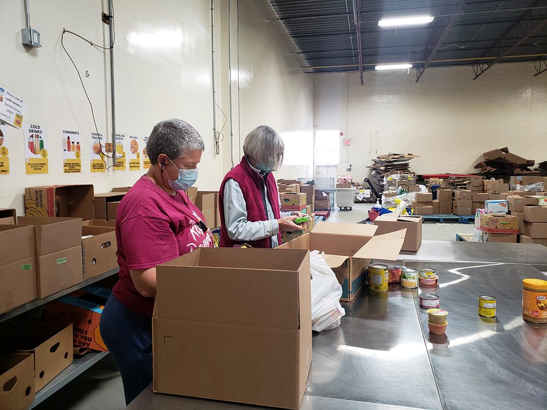 Feed the Need volunteers then sort through donated food, removing damaged and half-eaten donations as they sort the food into catagories seen on the wall behind them.