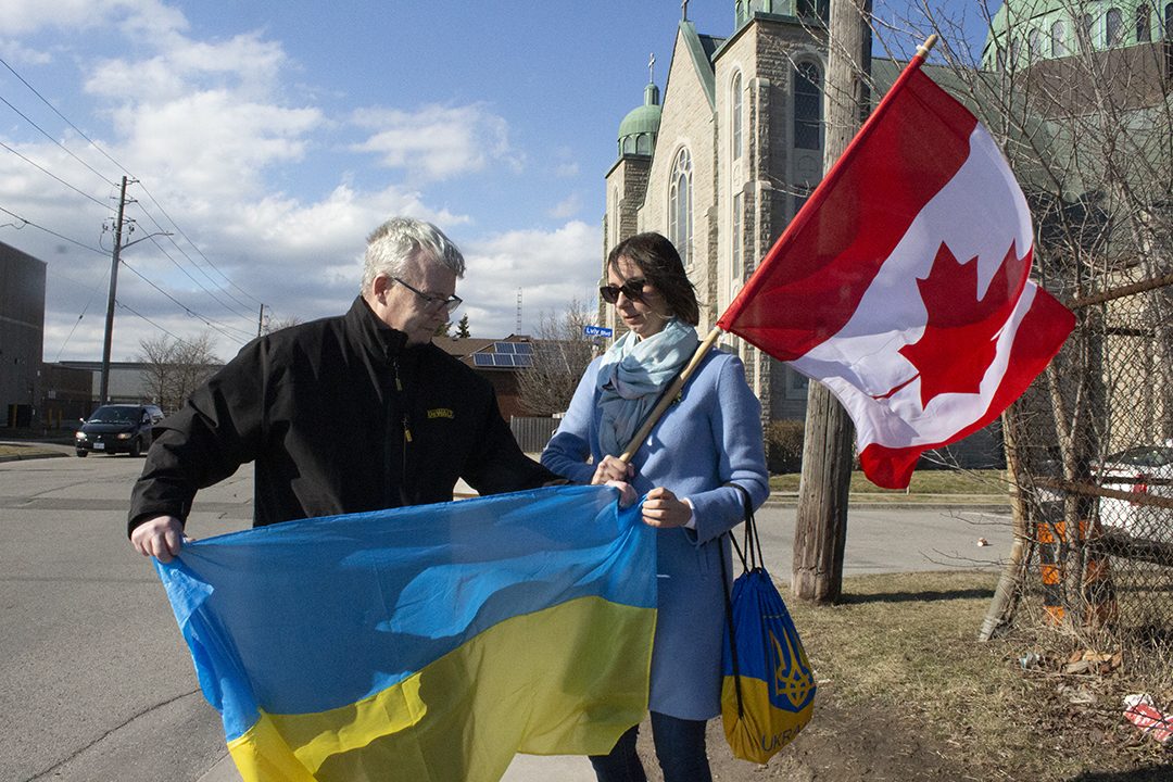 John Henry and Kateryna Rohowska hold flags.