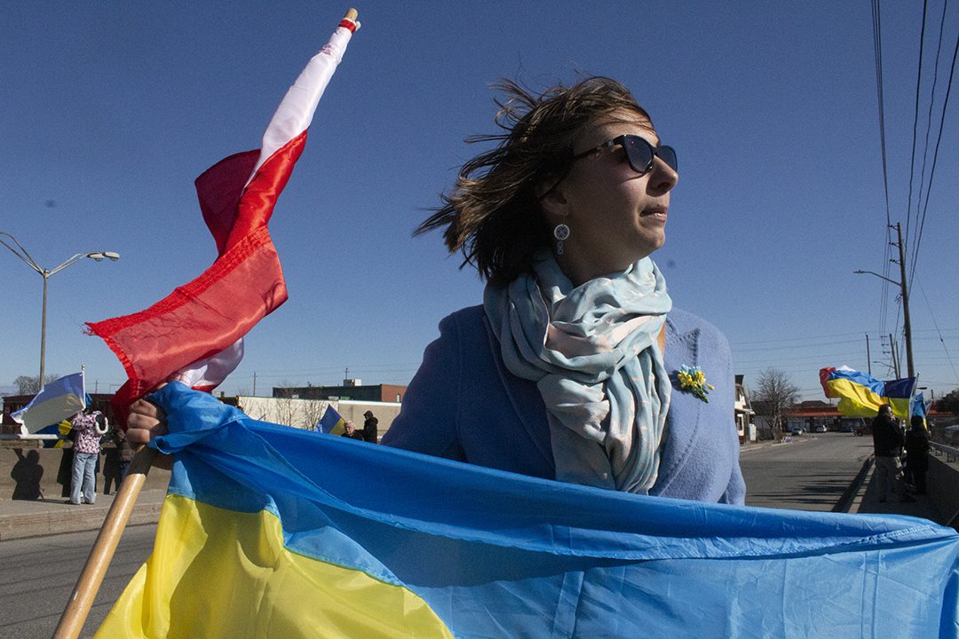 Kateryna Rohowska is dressed in blue and yellow as she holds the Ukraine and Canada flag.
