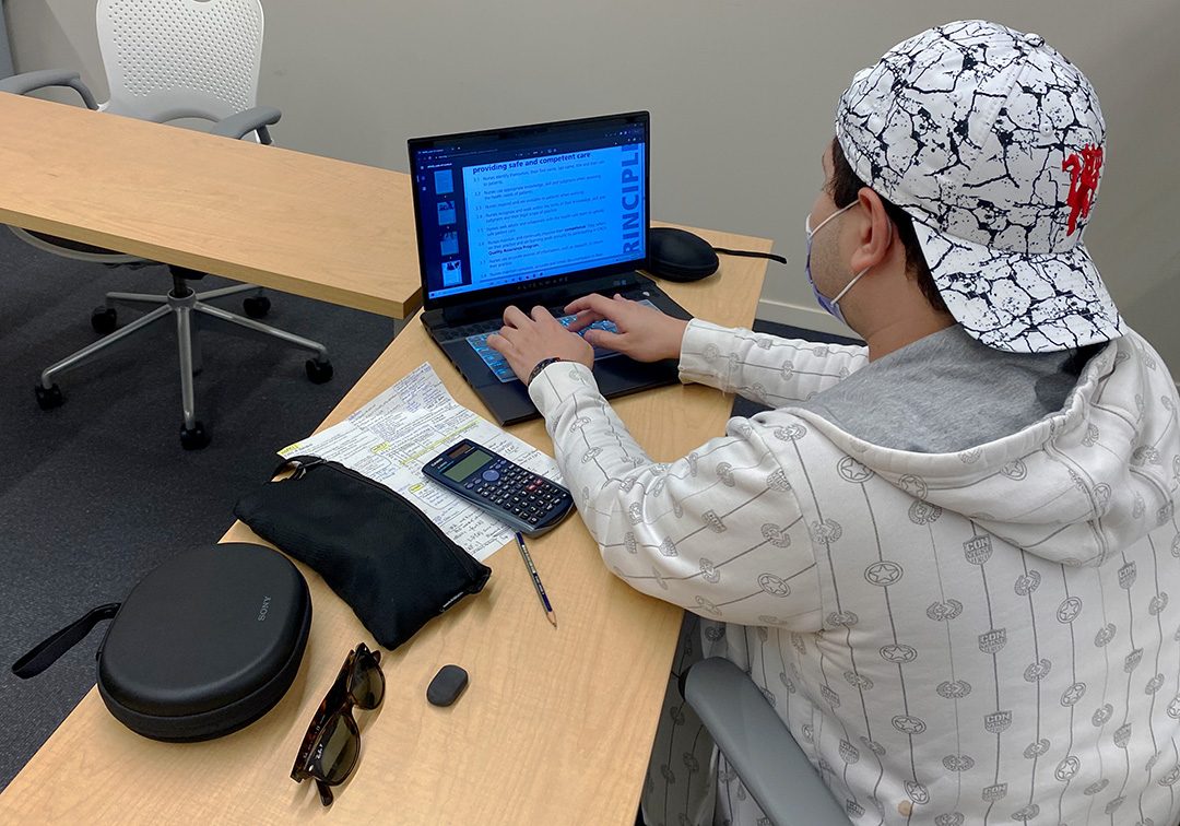 Ahmed Gamal studying for upcoming exams at the Energy Systems and Nuclear Science Research Centre (ERC) at Ontario Tech university. Gamal is typing hand written notes onto his computure. This help him to remember the information.