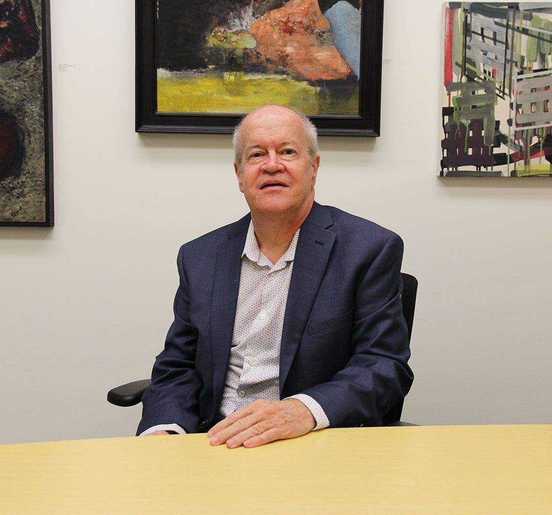 11/21/2022 - Barry Waite, Dean of Media, Arts & Design sitting at his office desk with his left hand on the table.