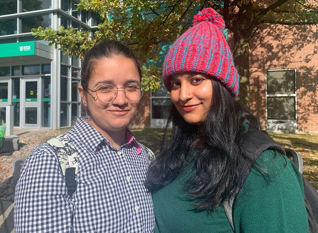 First-year international students Jyoti Kawatra and Nisha Kheewani wait for a bus together at Durham College.  Both students learned about the International Wellness Check at orientation.