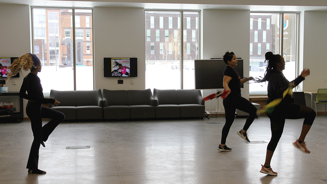 Community members dancing during a socacize fitness class. Some participants are also representing their backgrounds by waving their native flag.