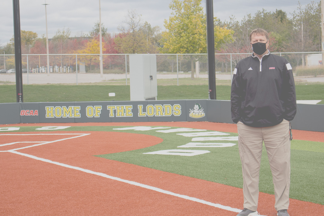 Ken Babcock standing on Durham Field, hometurf to 20-time OCAA champions women's softball program.