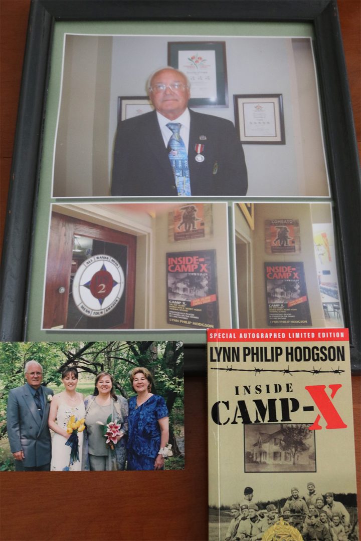 A framed photo of Lynn after receiving an award, as well as a photo of his book, 'Inside Camp X', and a poster at Camp X. A photo of Lynn and his children Renee and Karen and his wife Marlene.