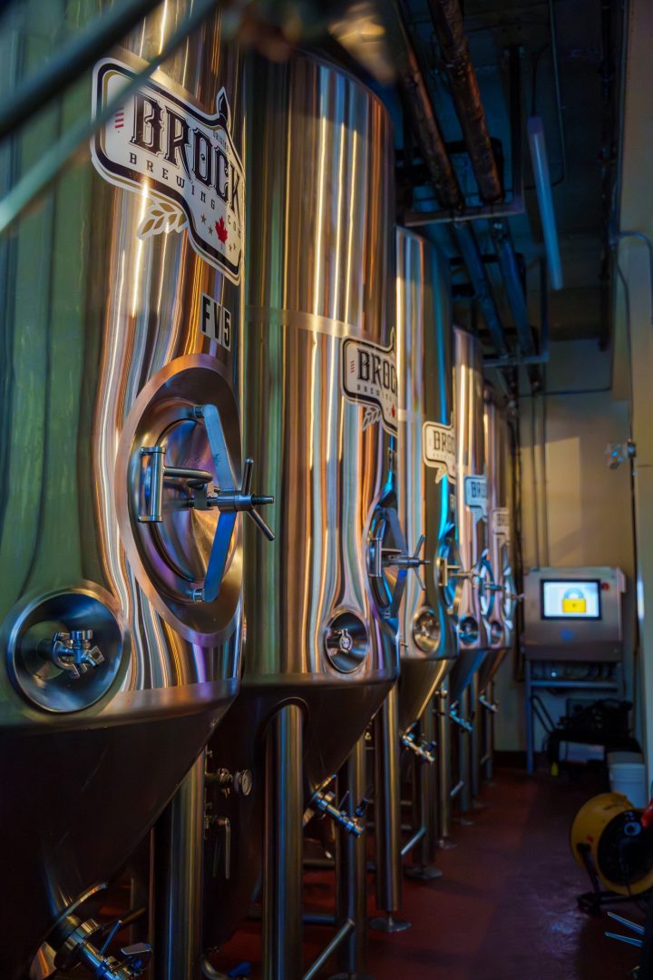 Four stainless steel tanks of brewing beer shine with light reflected through a restaurant window at Brock St Brewing's Whitby, Ont. location.