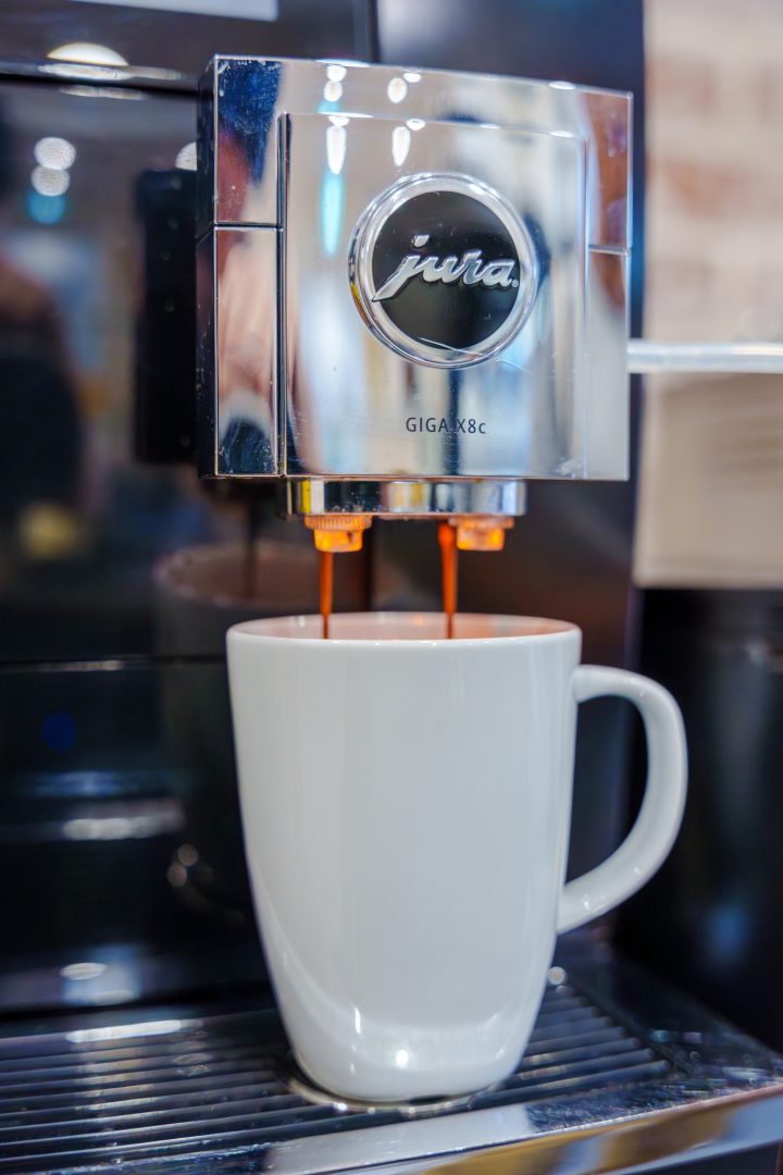 An espresso machine pours espresso into a white ceramic mug through two spouts.