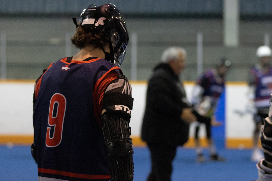 The back of a player wearing the number nine jersey. He is looking at the ground.