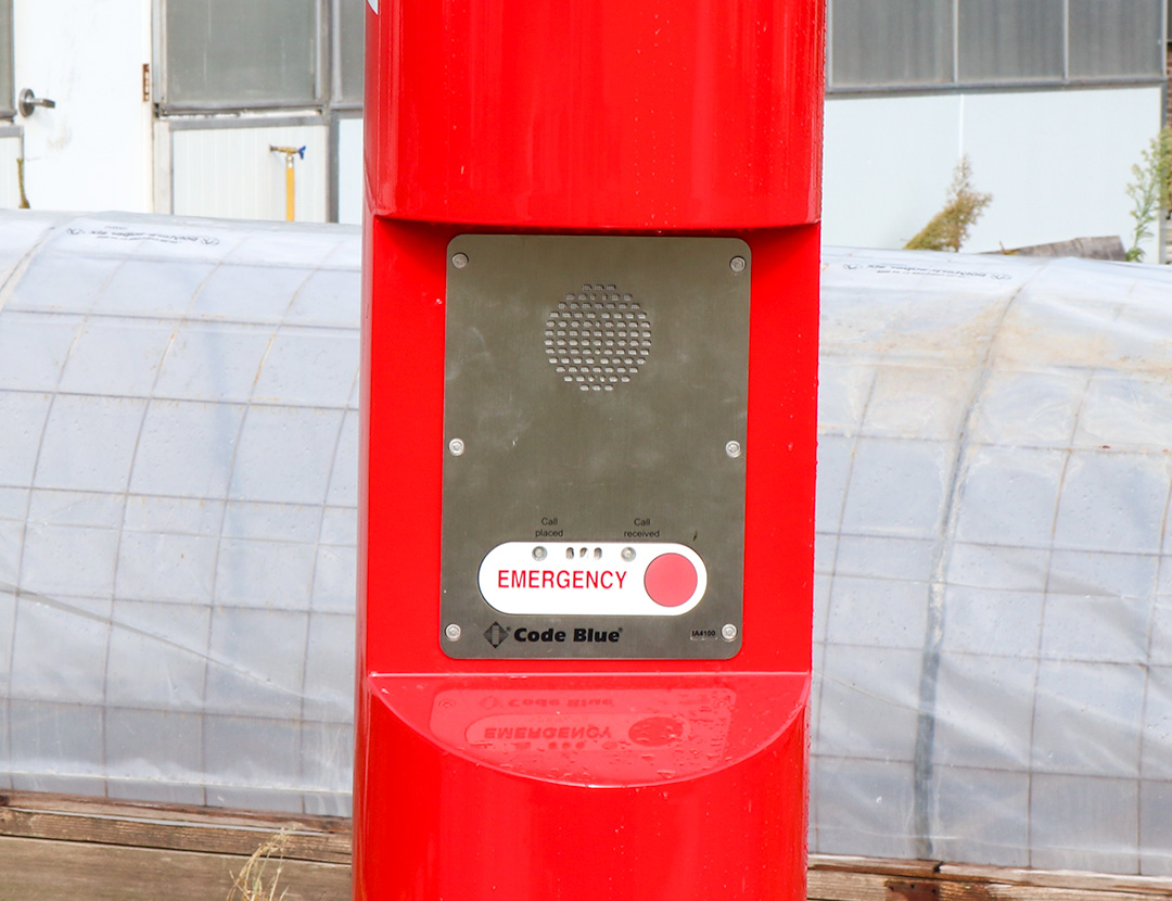 A red pole with a speaker and emergency button.