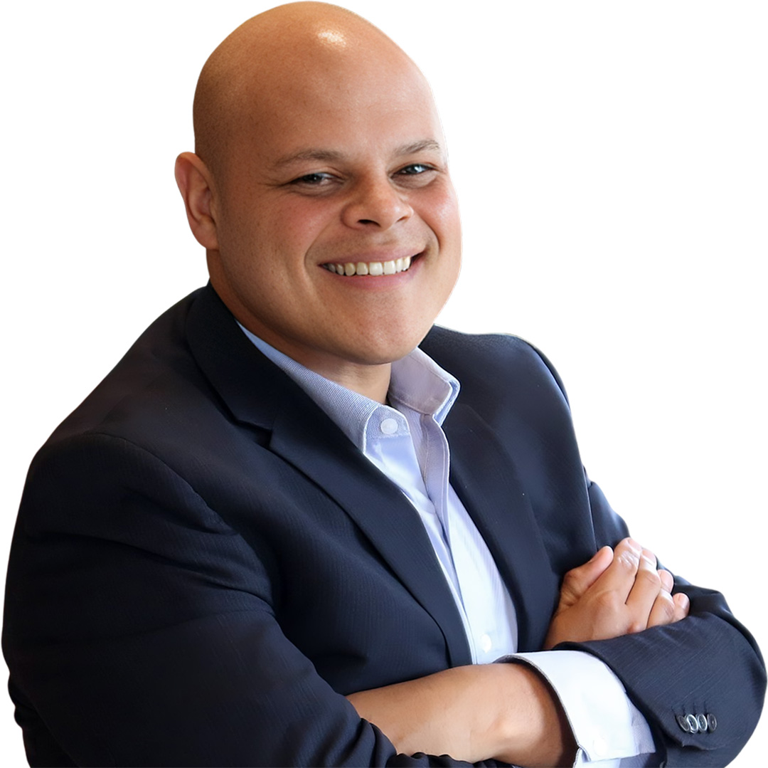 A headshot of Conservative Party candidate Jamil Jivani with arms crossed, smiling behind a blank background.