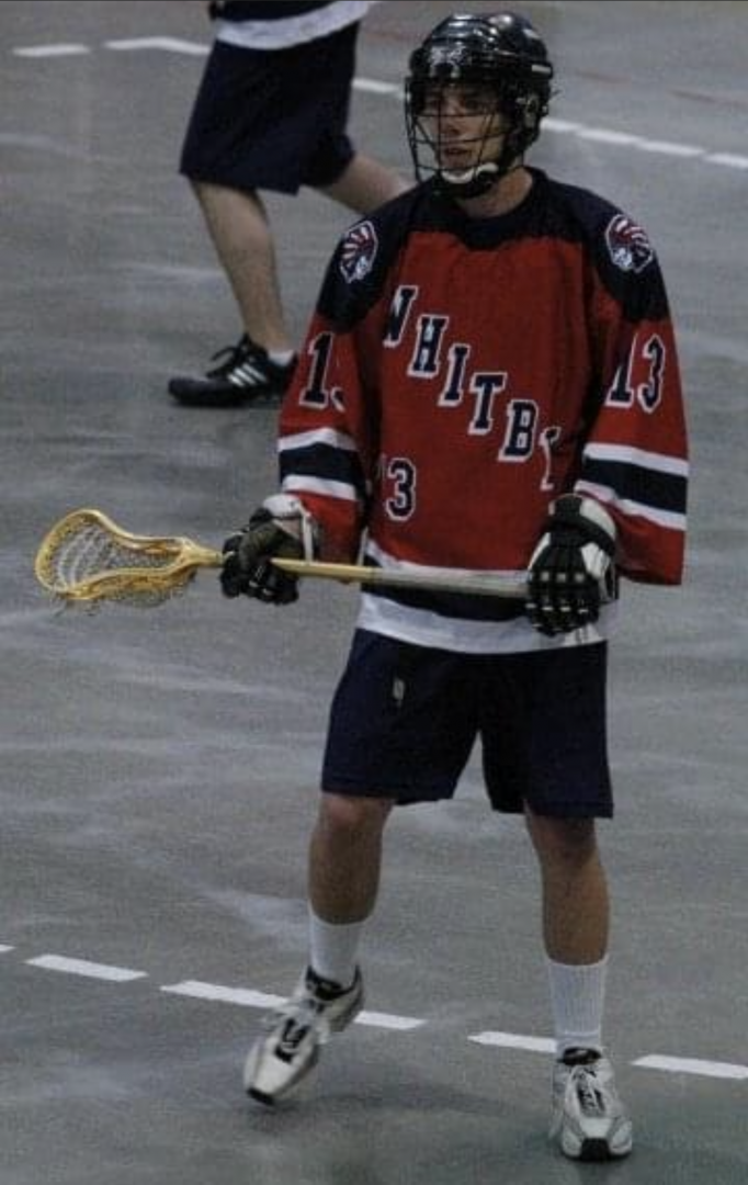 Jacob Powless holding a lacrosse stick wearing a red jersey