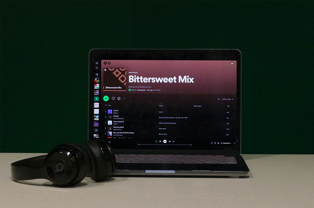 Bittersweet Mix is displayed on a laptop that has Spotify open, with a pair of headphones placed beside it.