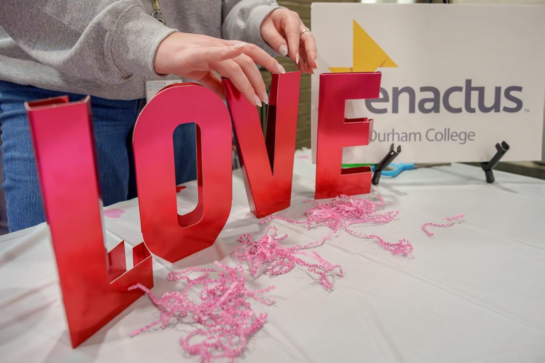 The word 'Love' displayed in big red letters along with the Enactus Durham College logo at one of the stalls during the Valentine's Day Market.