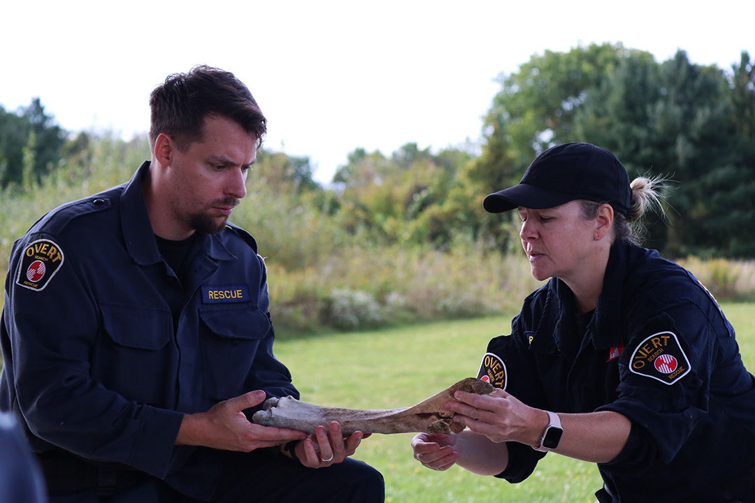 Two people (Jacob Clutter and Jennifer Newton) hold an animal bone between them in a park.