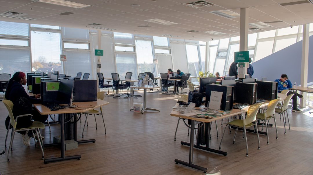 In the picture you can see the common space of the SALS with a lot of tables, chairs, computers and a few students seated here and there.