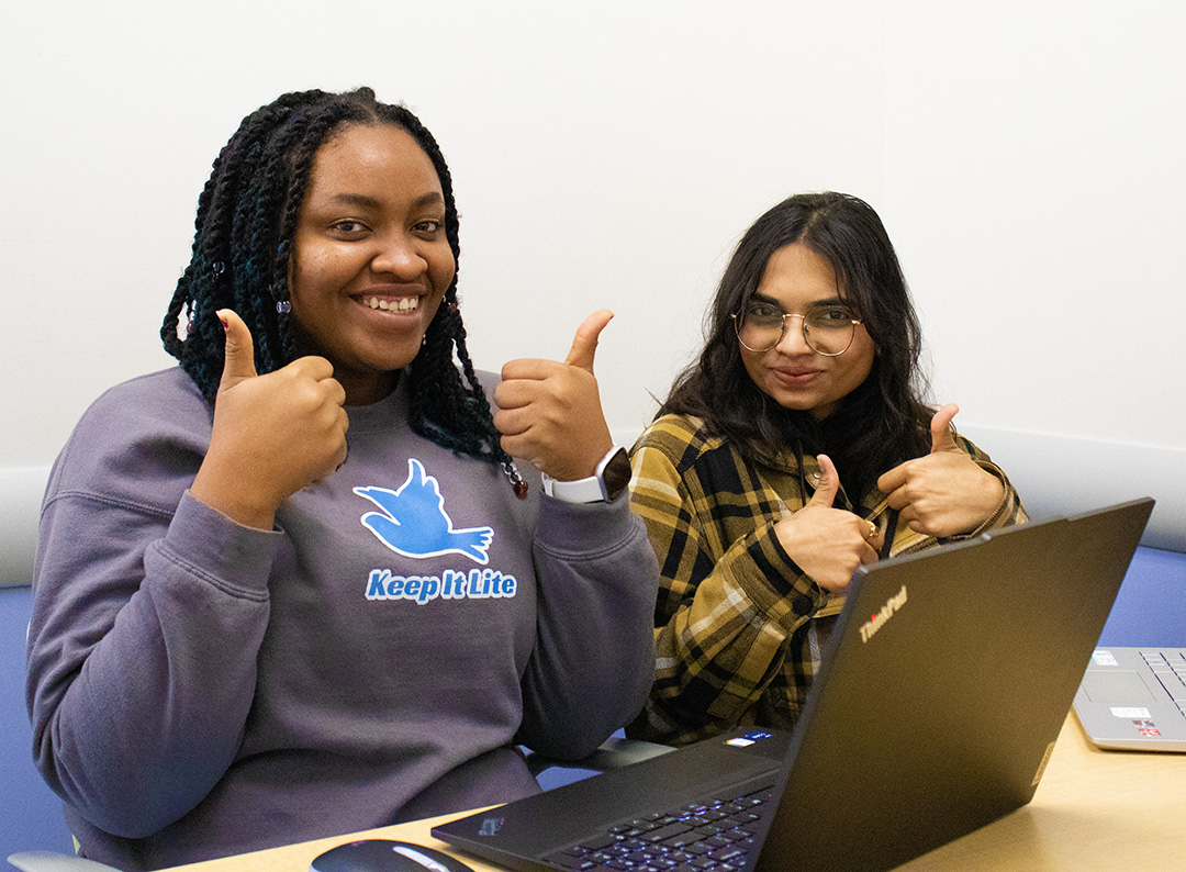 A student and a peer tutor can be seen smiling at the camera.