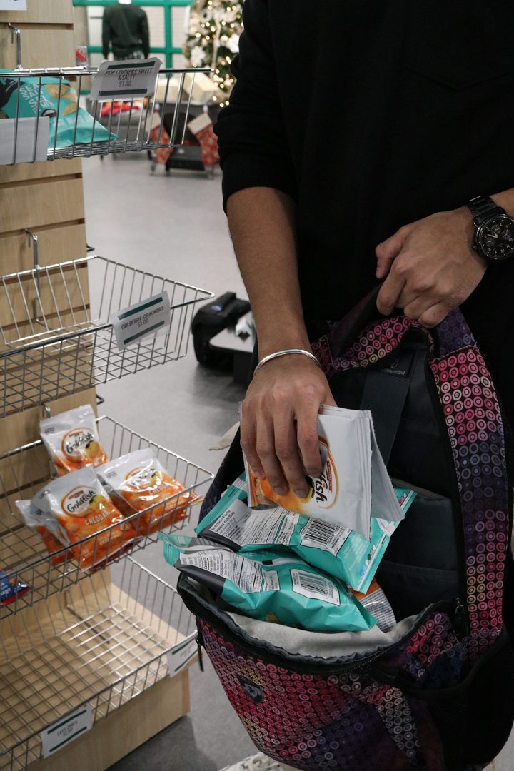 Durham College student urgently stuffing multiple bags of chips into an open backpack at the Durham College Campus store on Dec. 2, 2024. This photo is meant to illustrate an example of how some individuals in the youth community have begun to shoplift at stores.