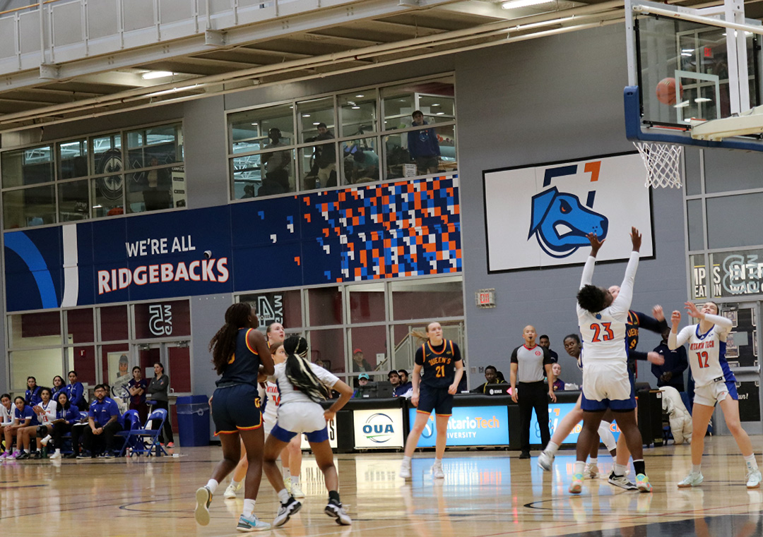 Coaches and players alike, watch on as a shot goes up in the Campus Health and Wellness Centre Gym, in a game between the Queen's Golden Gaels, and the Ontario Tech Ridgebacks, in Oshawa, Ontario, on Wednesday, Jan. 15, 2024.