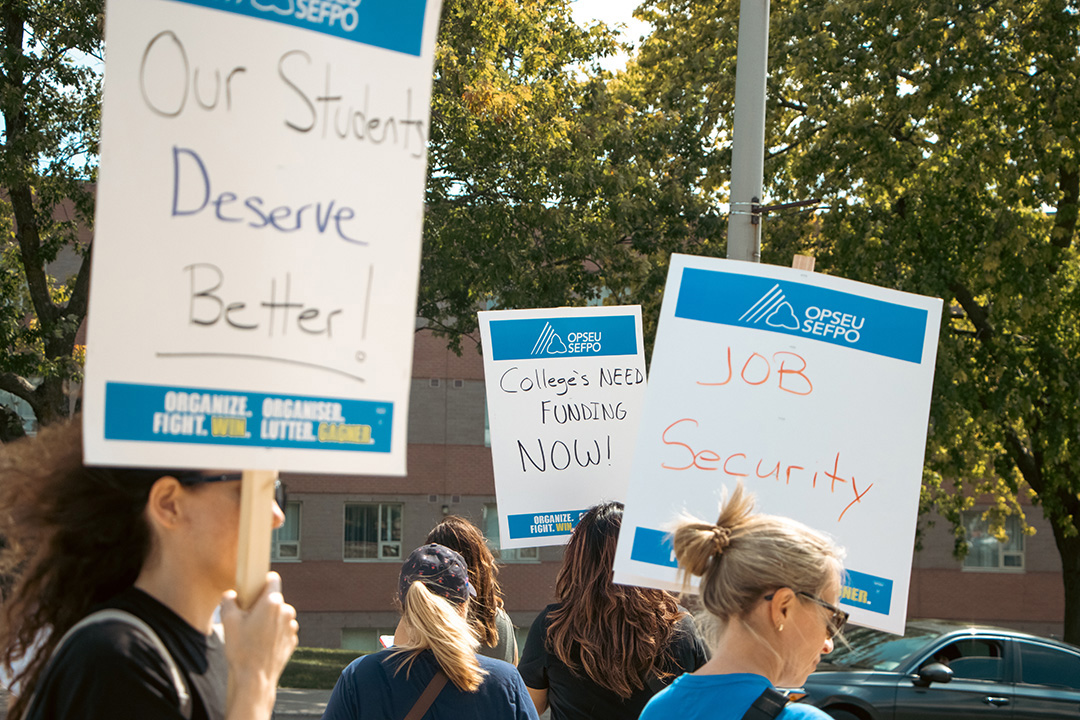 Picketers hold signs that say "Our students deserve better" and "Job security."