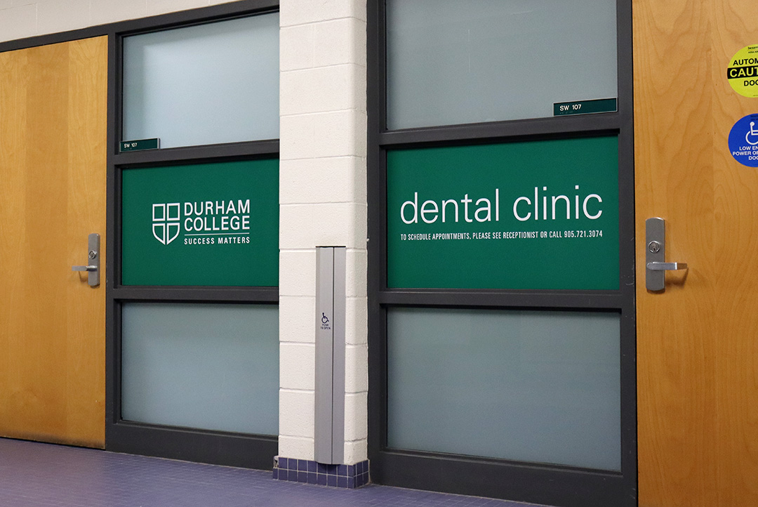 A green dental clinic sign outside an office.