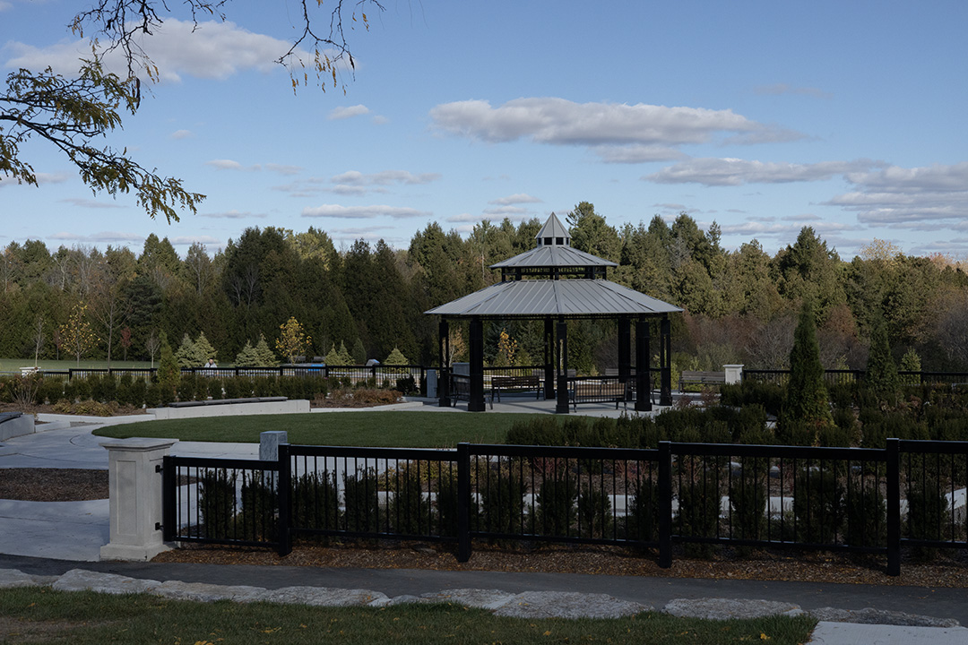 A pavilion stands in a park with a forest in the background.