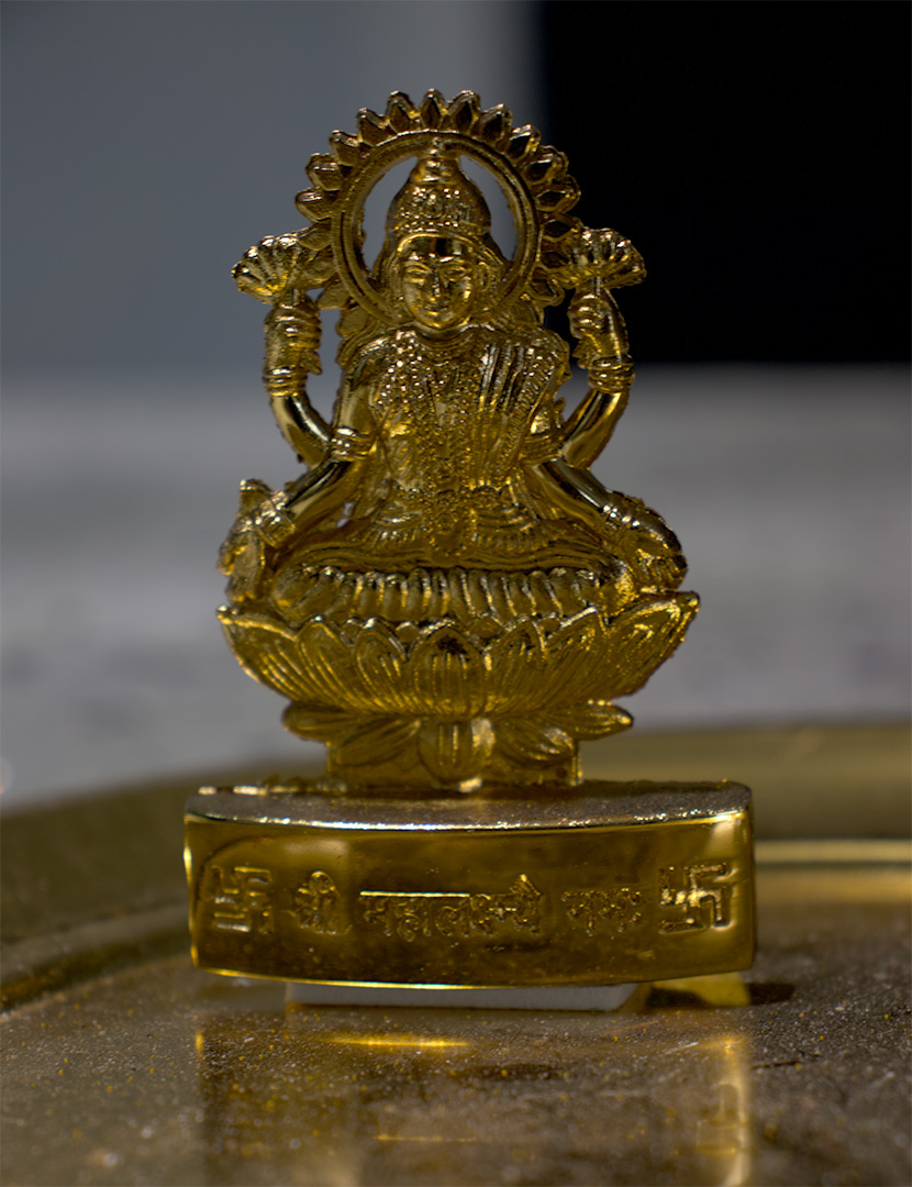A golden god sitting on a lotus flower. The idol is made of metal.