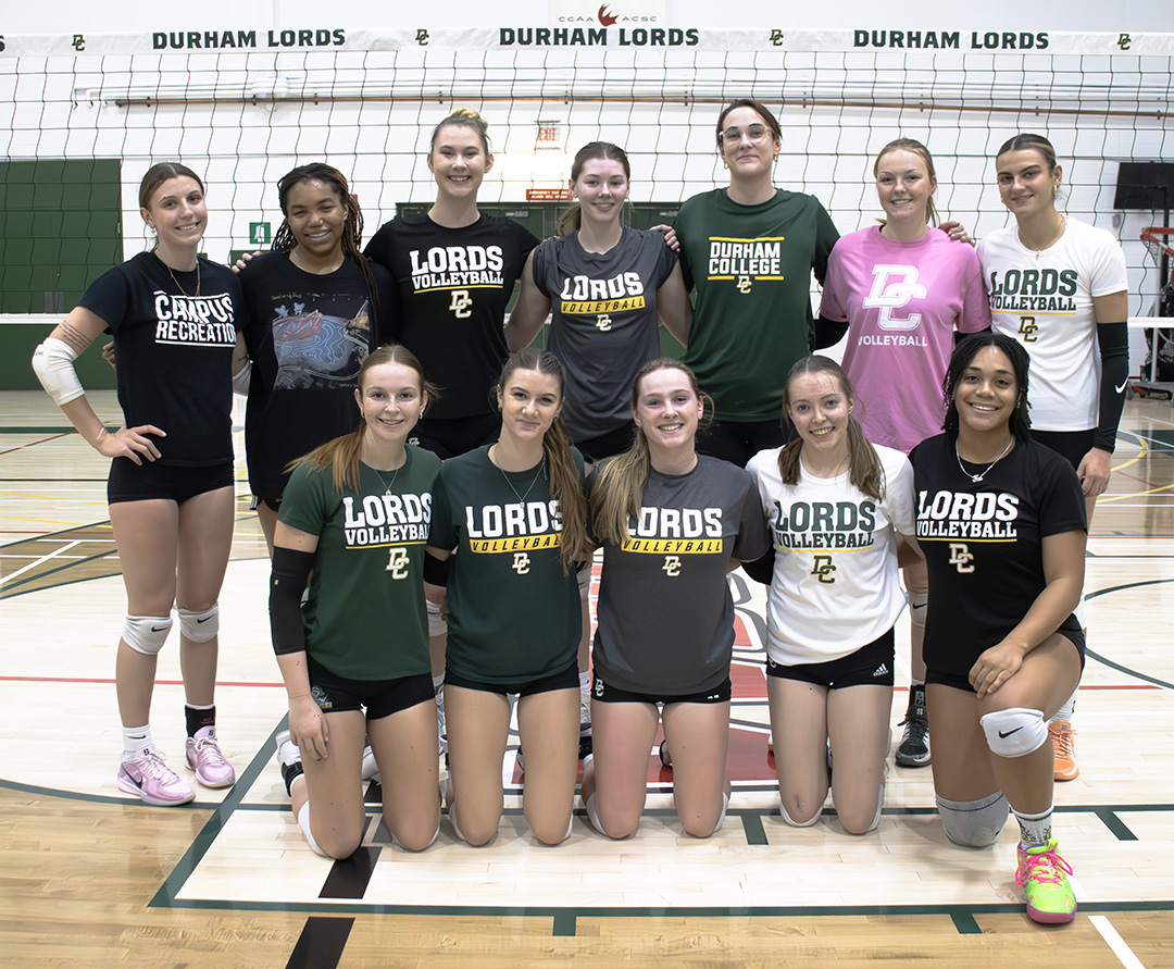 A group of female volleyball players stand together for a photo.