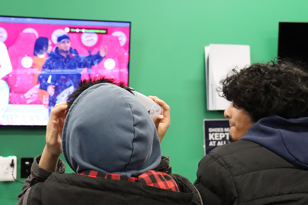 Two men look at a TV screen displaying a soccer video game.