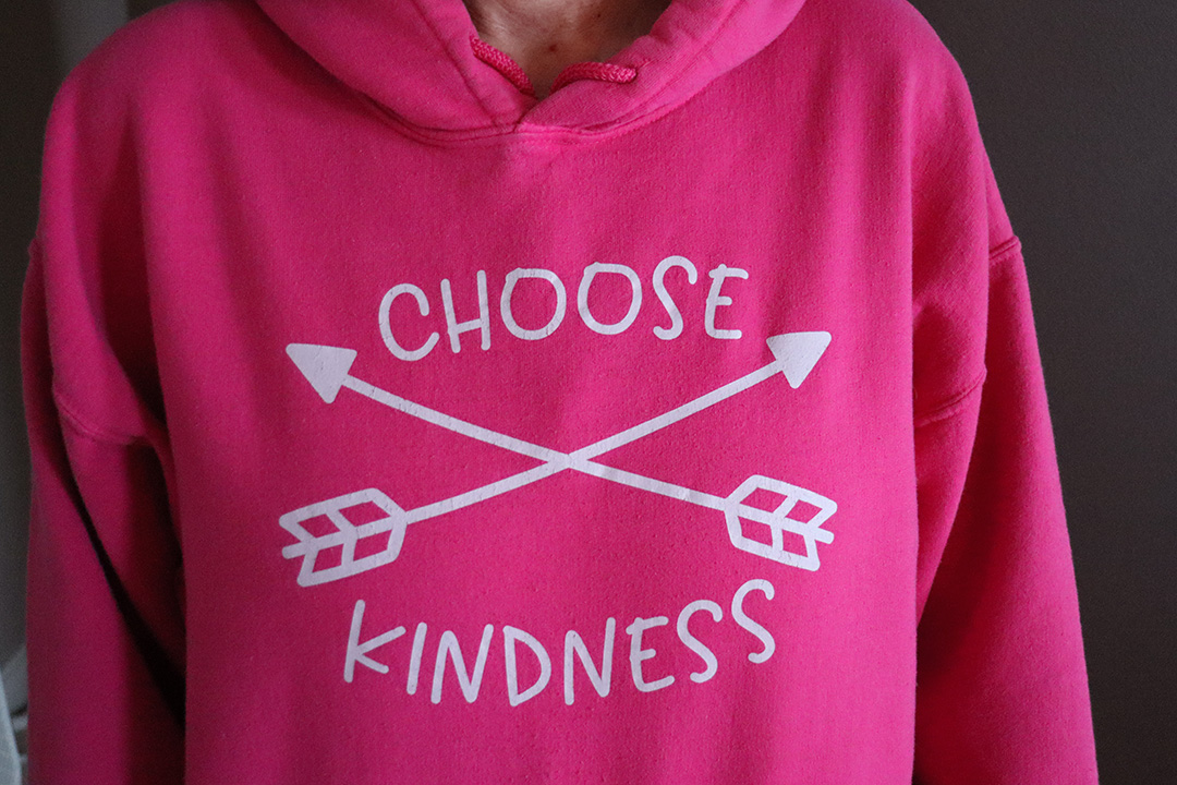 A close-up of a pink hoodie that says "choose kindness."