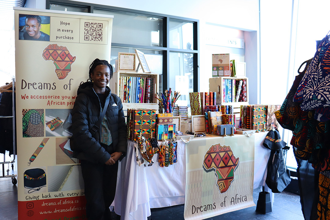 A young woman stands next to a table displaying various handmade accessories.