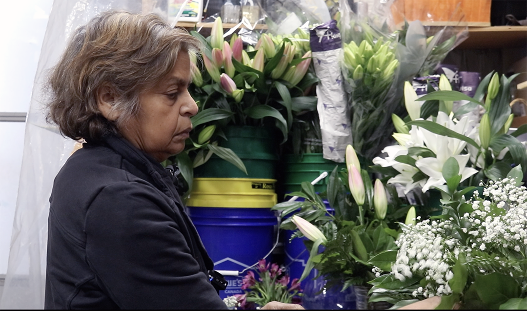 A woman stands arranging a bouquet of white and pink flowers.