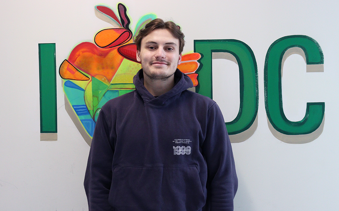 A young man looks at the camera, standing in front of a wall in the Oshawa campus of Durham College