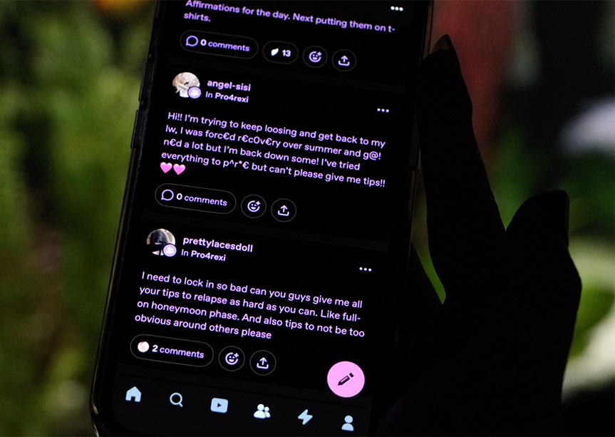 A hand holding a phone showing social media comments.