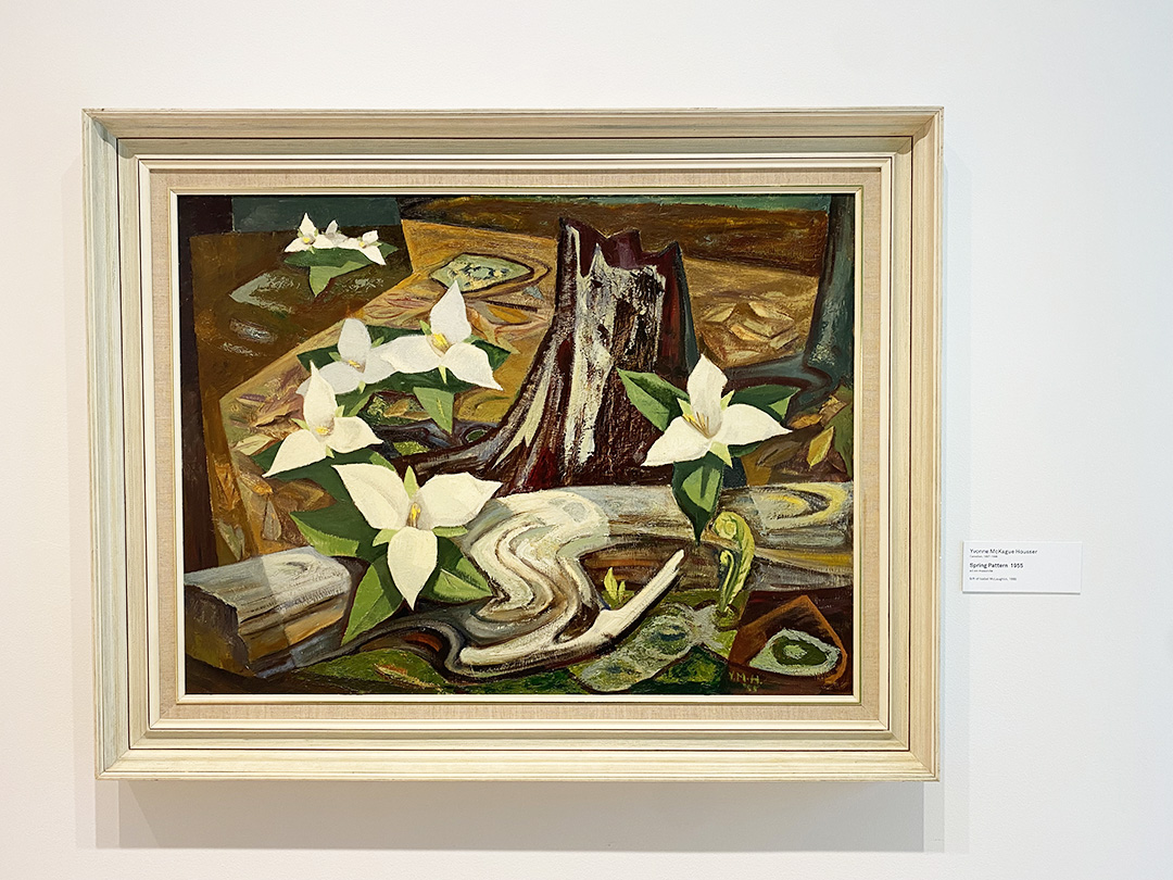 A framed painting on the wall with trilliums and background strokes of brown, orange and green.