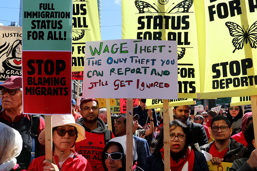 Protestors carry signs that say things such as 'Wage Theft: The only theft you can report and still get ignored.