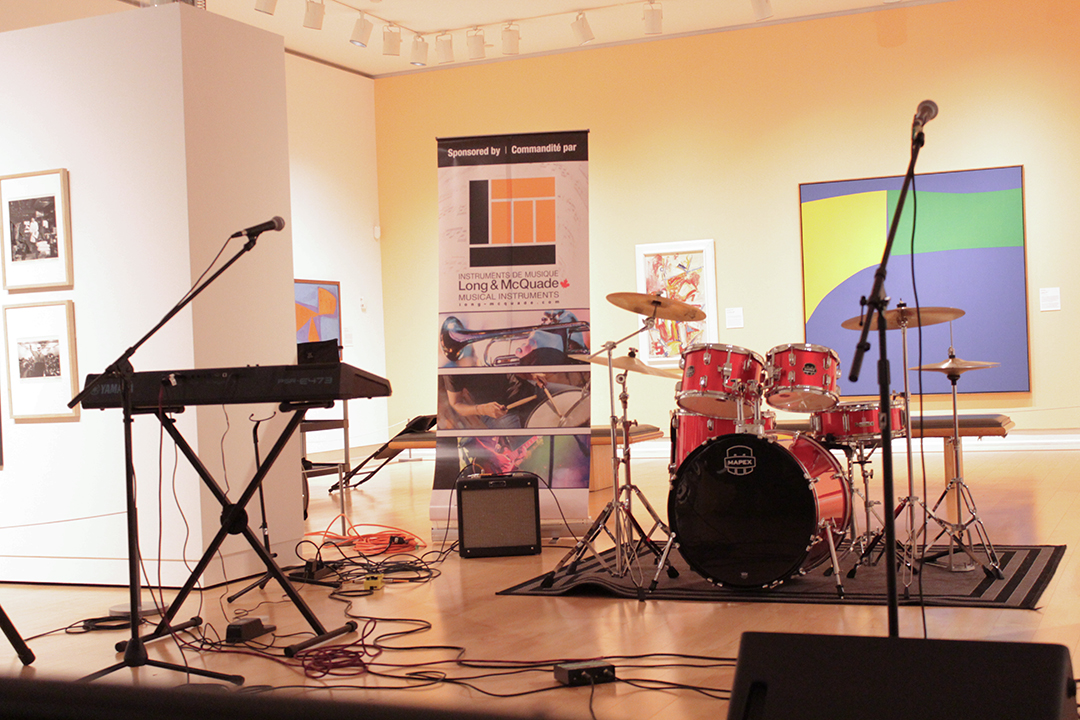 An empty stage featuring a keyboard, microphones and a drum kit